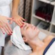 Beautician in a spa beauty salon applies cream to a client's face, a girl lies on a cosmetology table